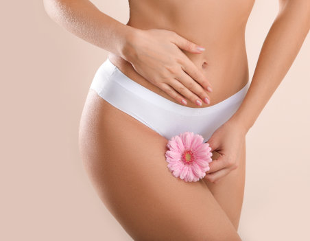 Young woman with flower on light background. Gynecology concept