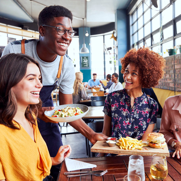 smiling waiter serving food to customers