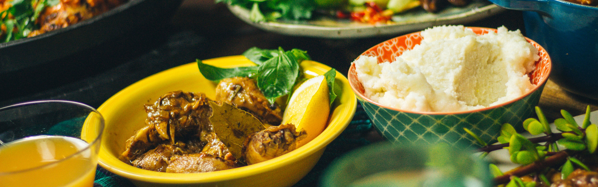 Feast of chicken dishes, salad and pap on a wooden deck