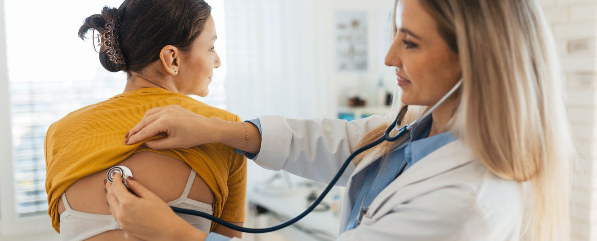doctor using stethoscope on patients back