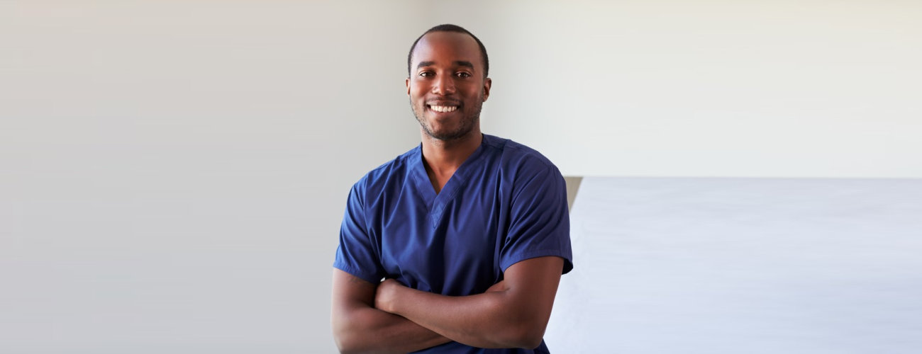Portrait Of Male Nurse Wearing Scrubs In Exam Room