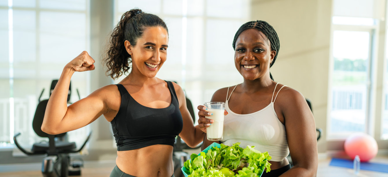 Two women are photographed indoors, smiling and looking toward the camera