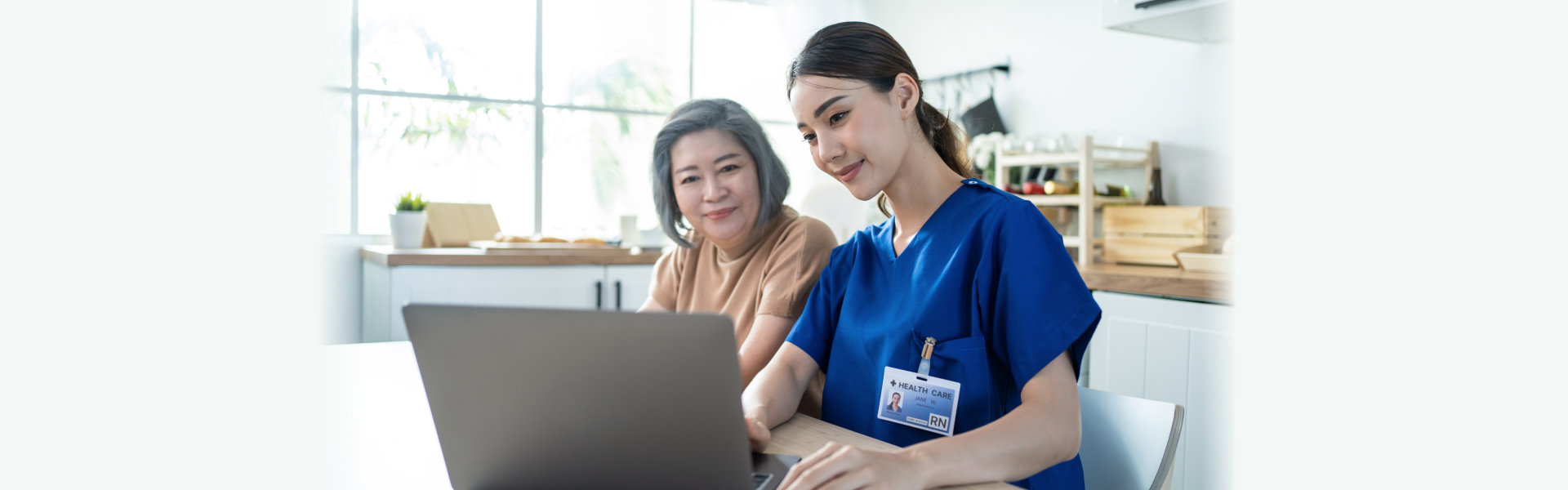 caregiver and senior looking at a laptop