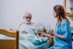 Nurse giving a glass of water to patient with pills